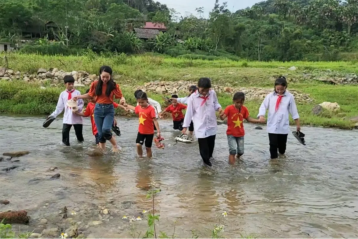 Cô giáo vùng cao dắt học sinh đi học qua suối nhỏ trong sương sớm