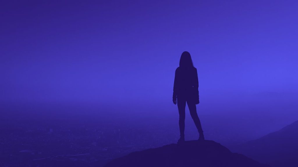 Cô gái đứng trên đỉnh núi, nhìn về phía chân trời, đại diện cho ước mơ và hoài bão lớn.